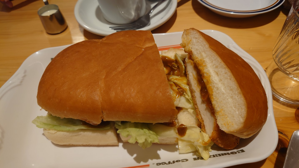 Large Komeda sandwich on a plate inside a Komeda coffee shop.