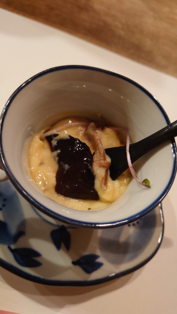Chawanmushi after a spoonful has been taken, showing the soft custard texture and ingredients inside.